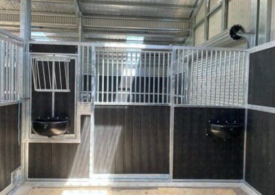 Inside of a horse stable with matching feed & water trough